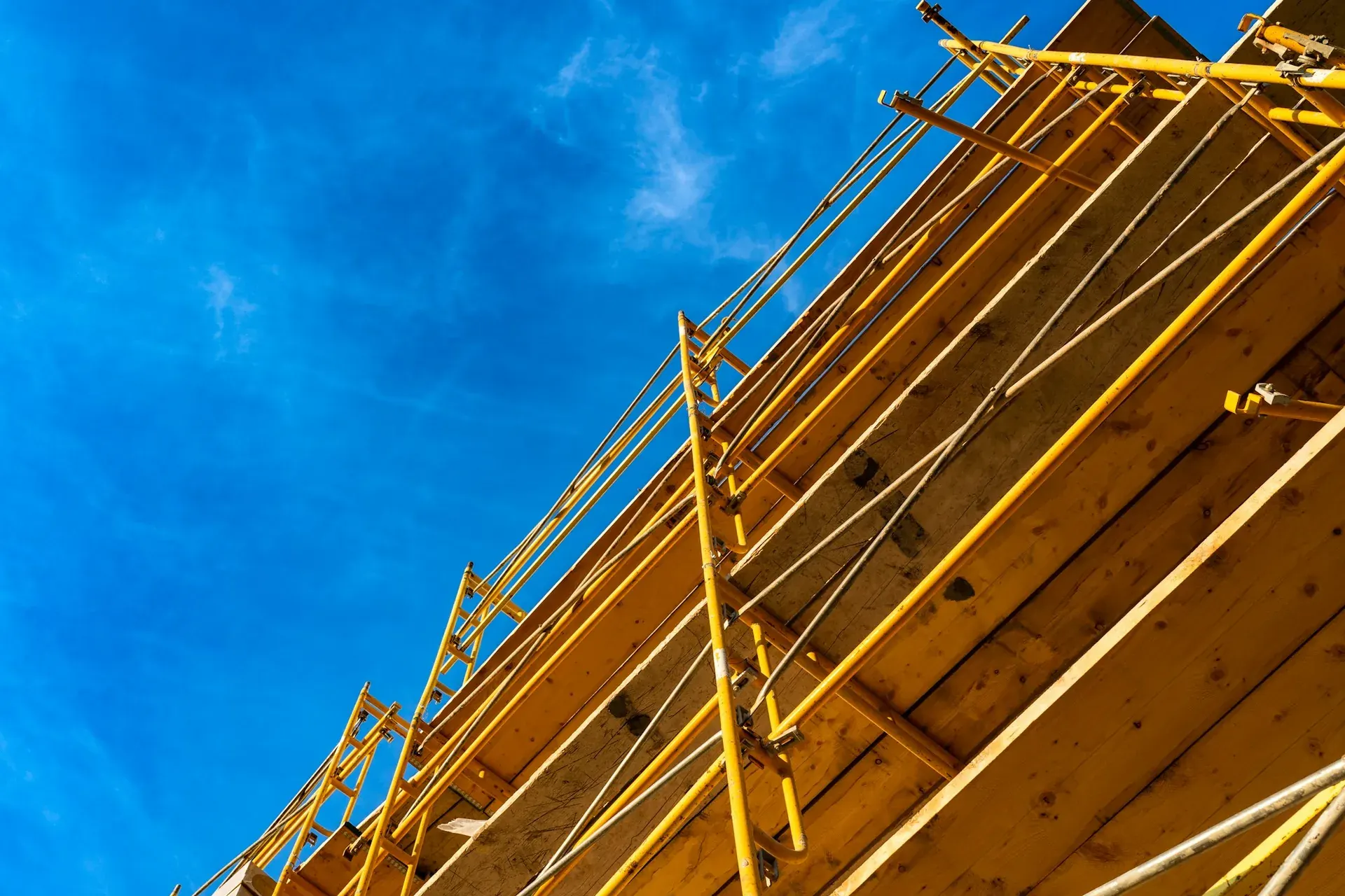 Yellow scaffolding running diagonally against a deep blue sky